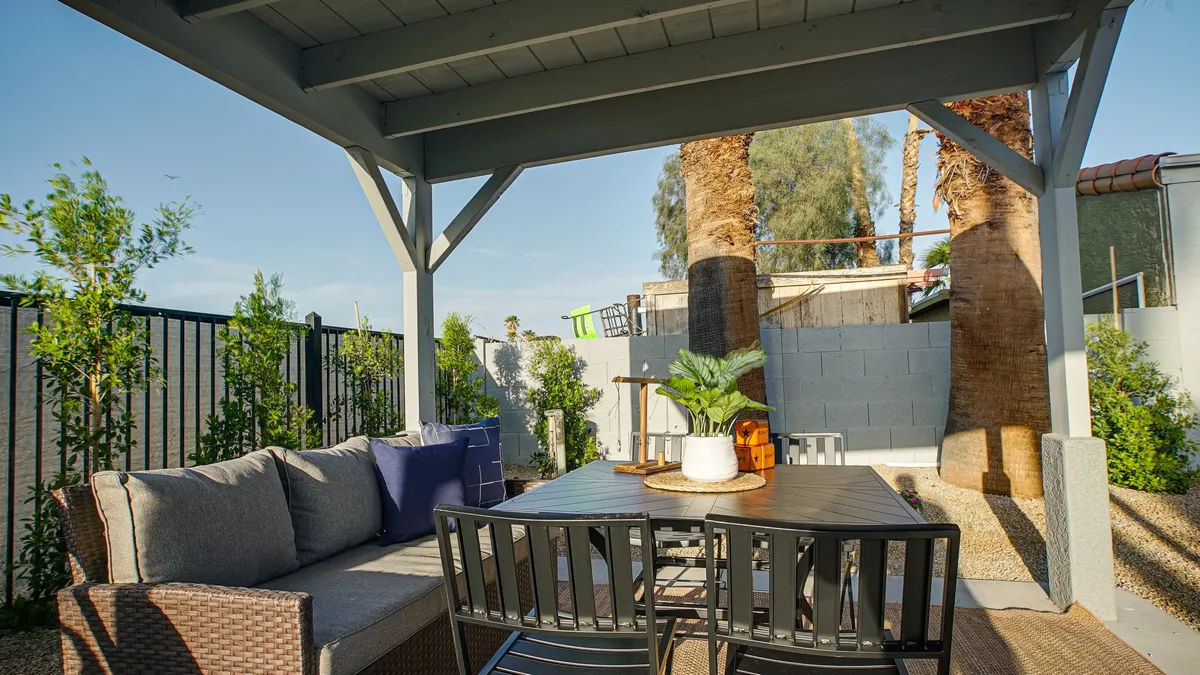 A spacious outdoor dining area is nestled beneath swaying palm trees, offering a communal table ideal for alfresco meals, morning coffees, or festive celebrations. The lush landscaping and tranquil mood set the stage for group gatherings and easy socializing.